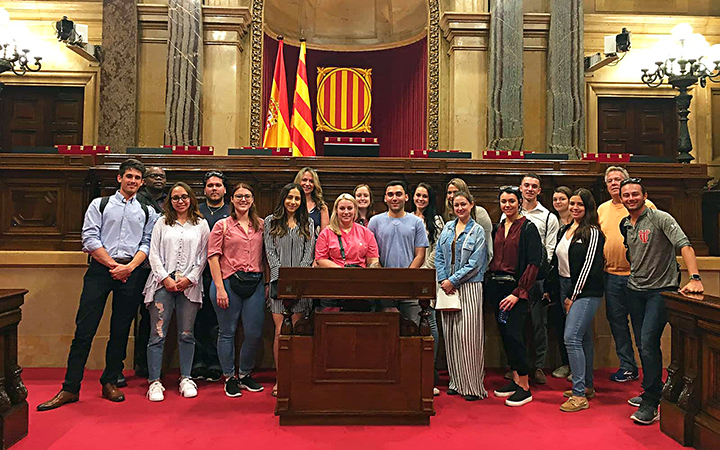 Students gather around a podium at the Parliament of Catalonia during a criminology travel course.
