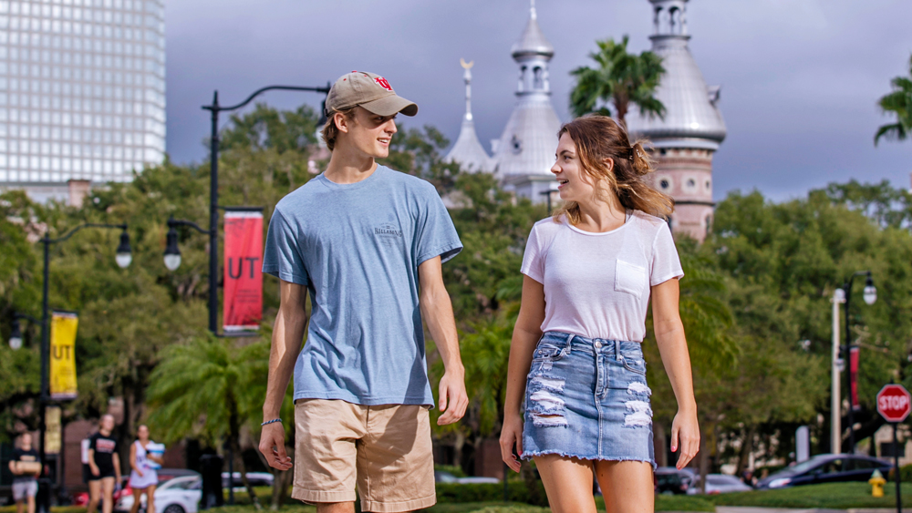 Students walking on campus with minaret and downtown Tampa behind them