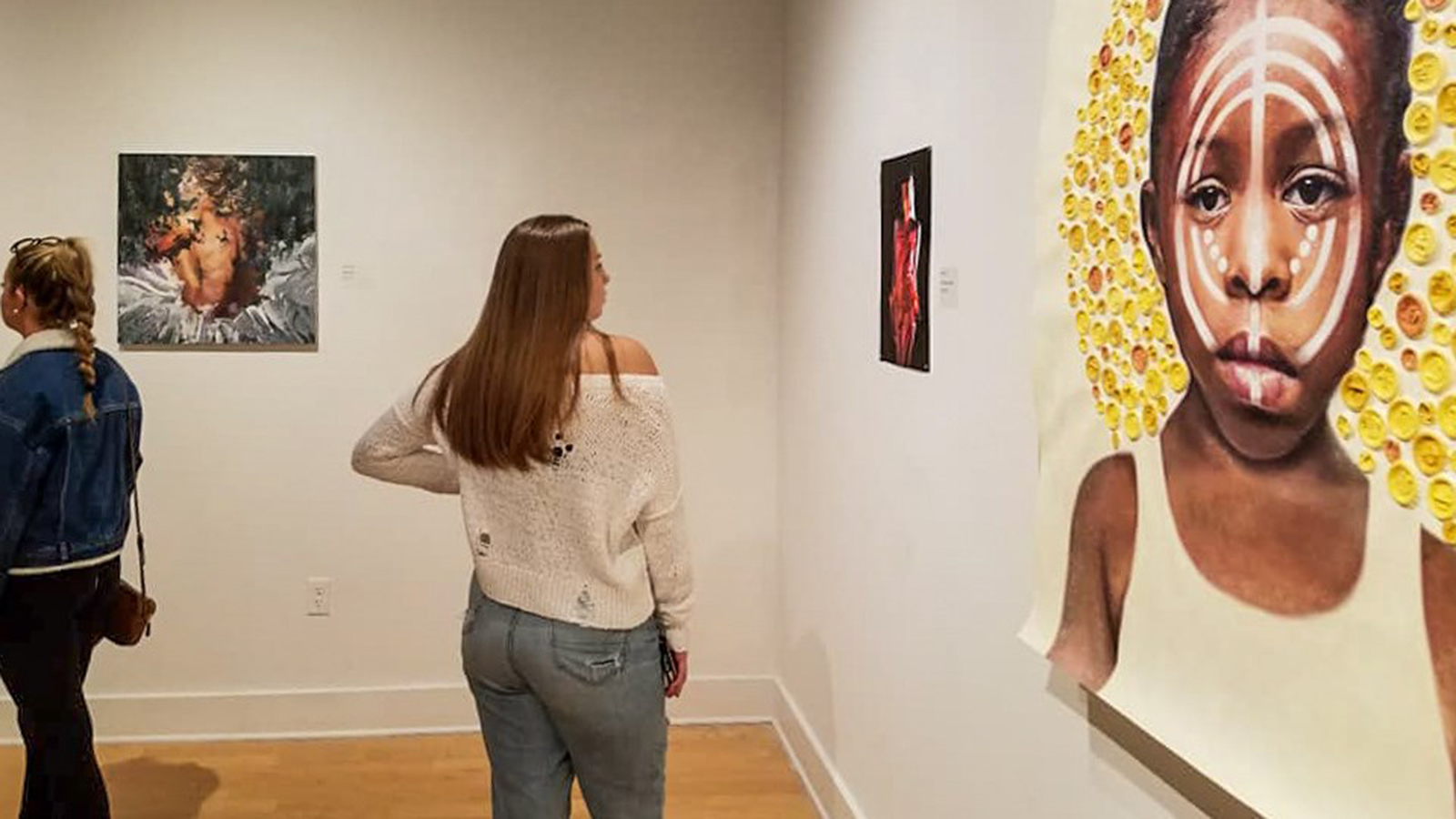 A student looking at artwork in the Scarfone/Hartley gallery.