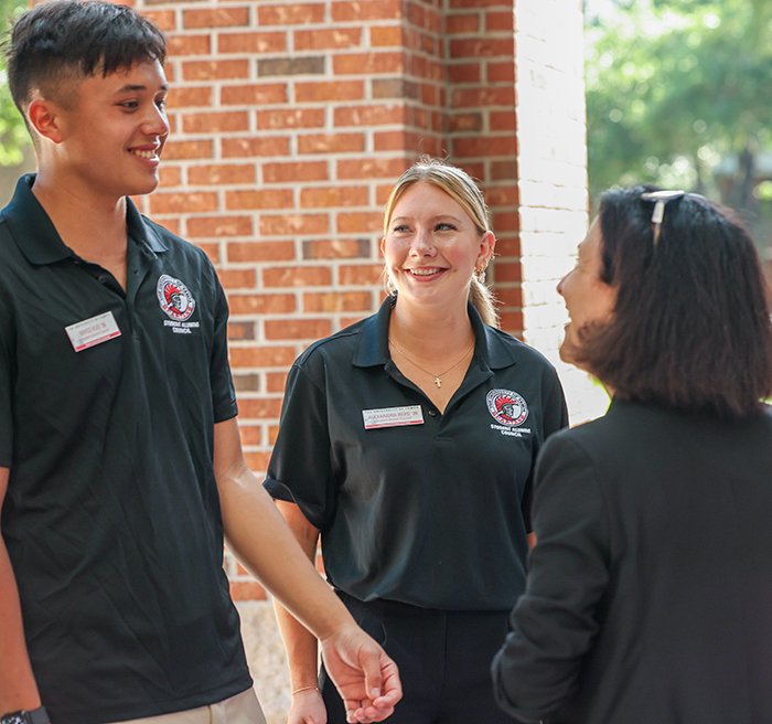 President Dahlberg talking with two students during inauguration week. 