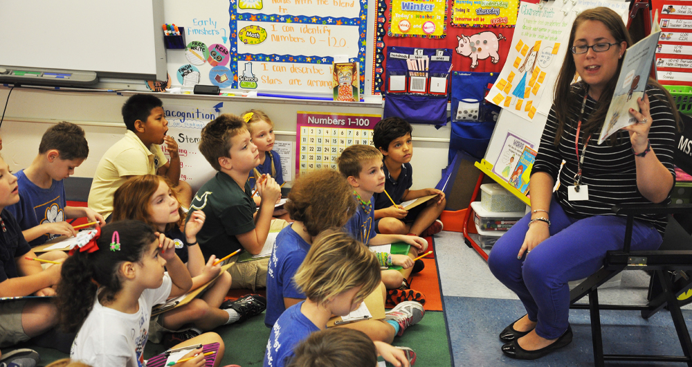 Teacher reading to a class of students teaching reading story to elementary students