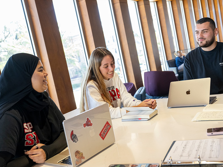 Three students sitting together and working on their laptops