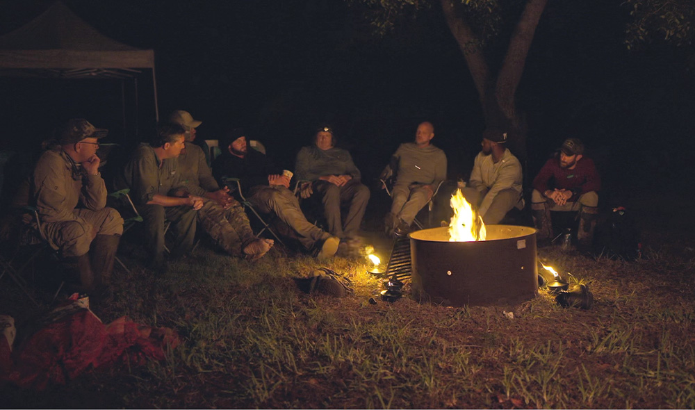 Men sit around fire outside