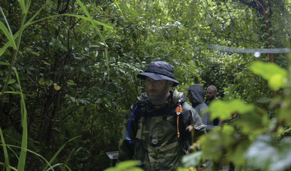 Man walking in woods with hat on
