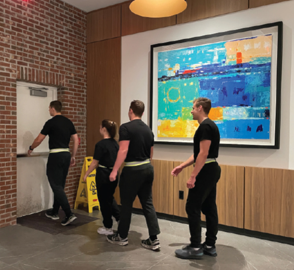 FOUR PEOPLE DRESSED IN BLACK WALK OUT OF A DOOR