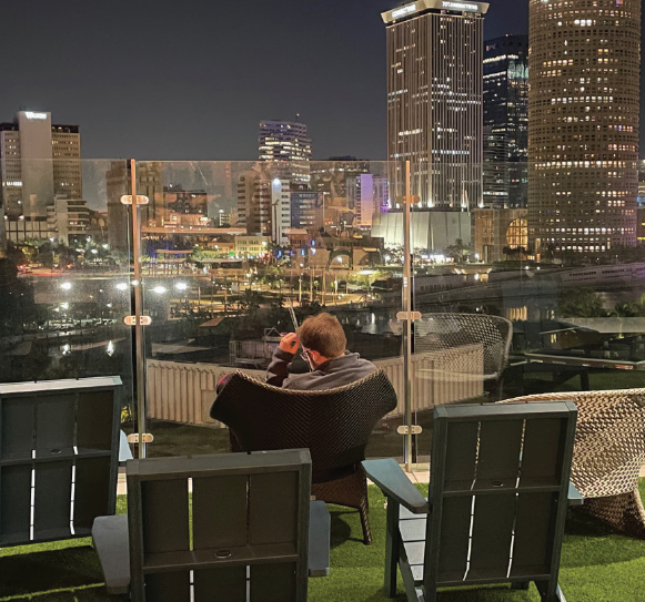 A MAN SITS OVERLOOKING THE CITY LIGHTS AT NIGHT