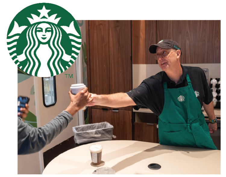 A BARISTA HANDS A CUSTOMER A CUP OF COFFEE