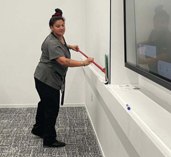A WOMAN CLEANS A WHITEBOARD IN A CLASSROOM