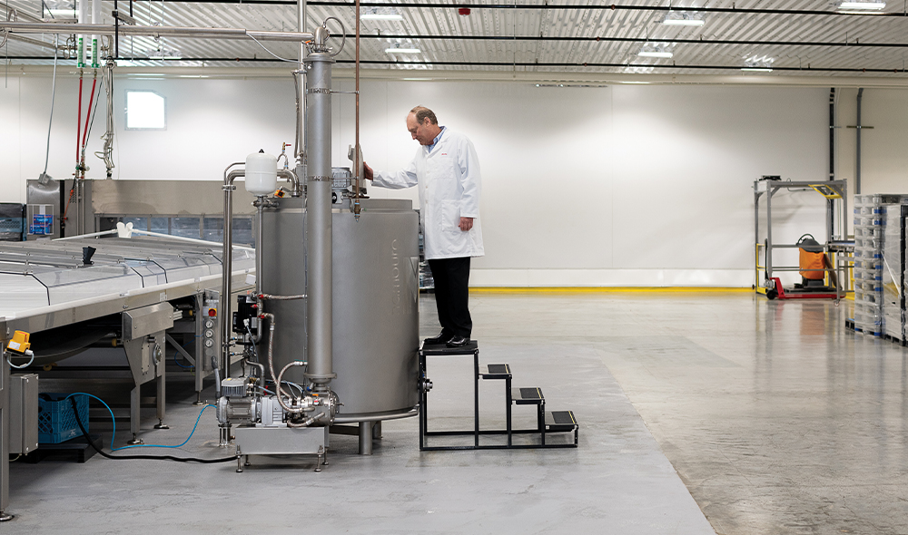 A MAN IN A WHITE LAB COAT LOOKS INTO A VAT