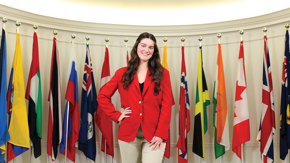 WOMAN STANDING IN FRONT OF FLAGS