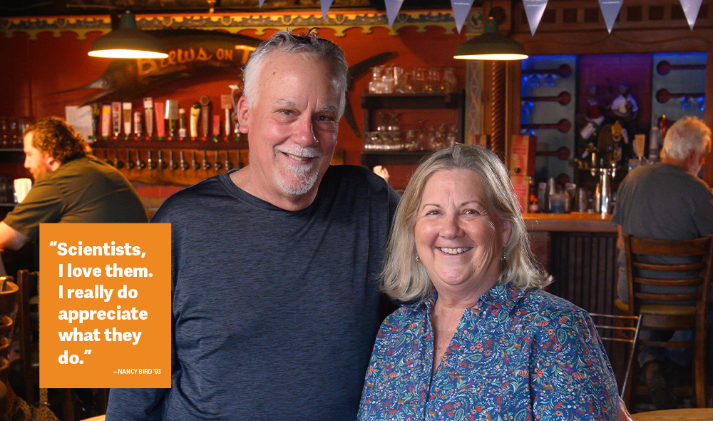A man and woman in a bar, smiling at the camera