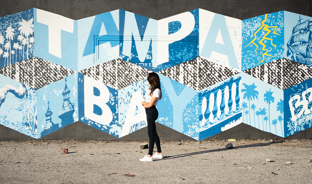 A large mural on a building split up by 5 pillars on a building 