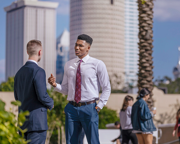 Students dressed in professional attire chatting with downtown Tampa in the backdrop.