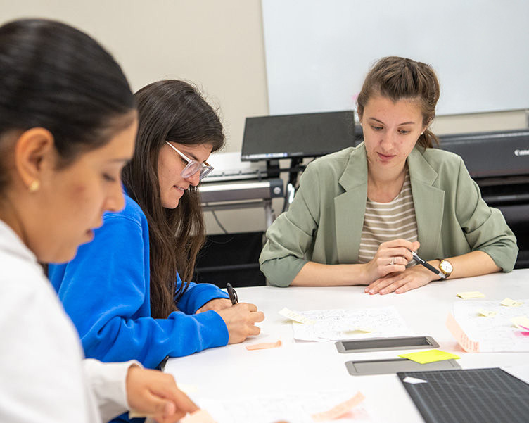 Professor working with two students in a classroom.