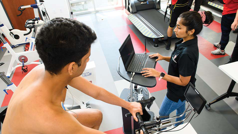 A human performance major measuring a person's readings while on a stationary bike. 