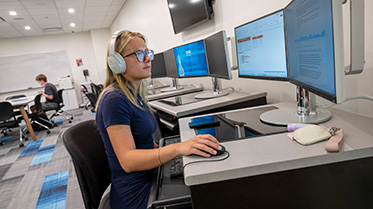 Student studying at a computer with headphones on.