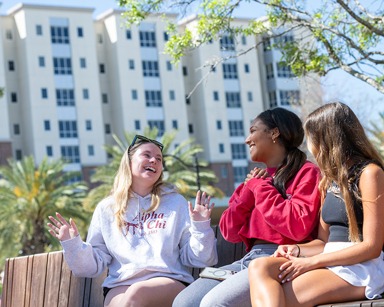 Students laughing on a bench in the Sykes Plaza.