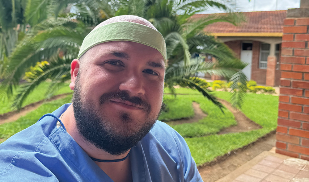 A MAN WEARING NURSING SCRUBS AND A HEADBAND OUTSIDE