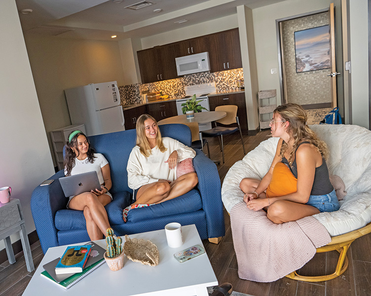 Three girls in their residence hall talking.