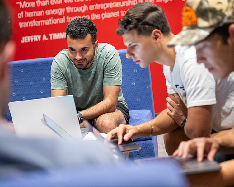 Three male students work on laptops.