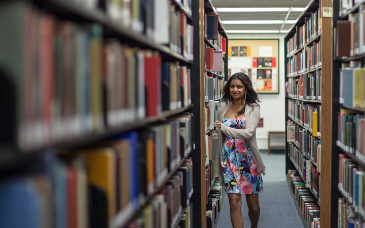 Lady walking down the aisles of a library