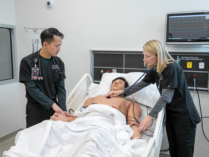 Physician Assistant students working on a mannequin in a bed