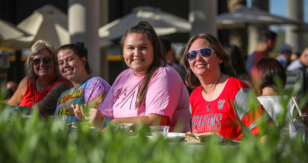 A student with her parent sitting at the tables outside Morsani.