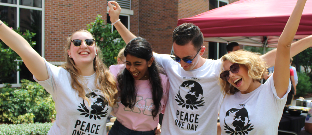 Four students with their hands up in the air cheering.