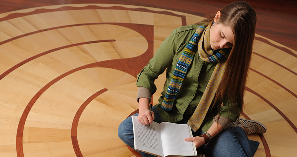 Student writing in a journal in the meditation center