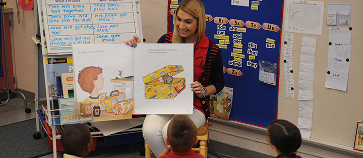 Student reading a book to children