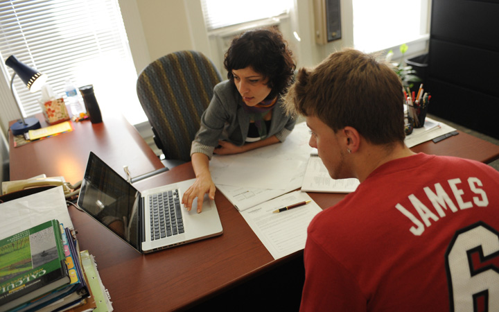 Two people sitting at a desk looking at a laptop