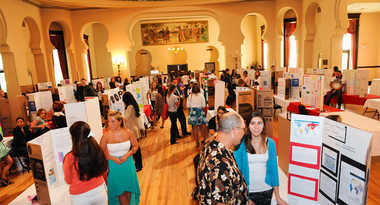 Students showing research posters at event
