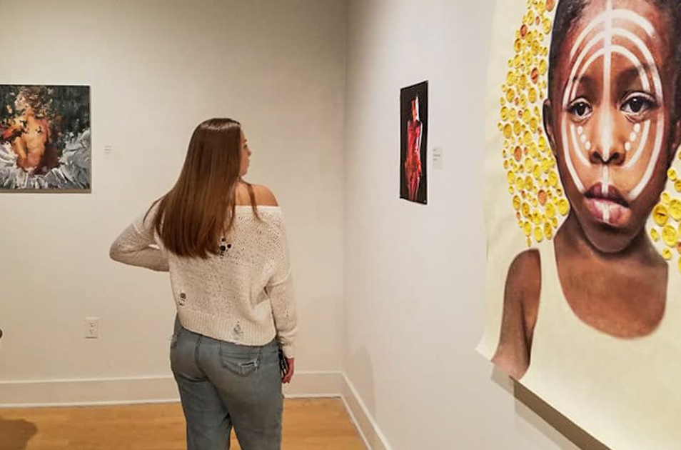 A student looking at a painting in the Scarfone/Hartley Gallery.
