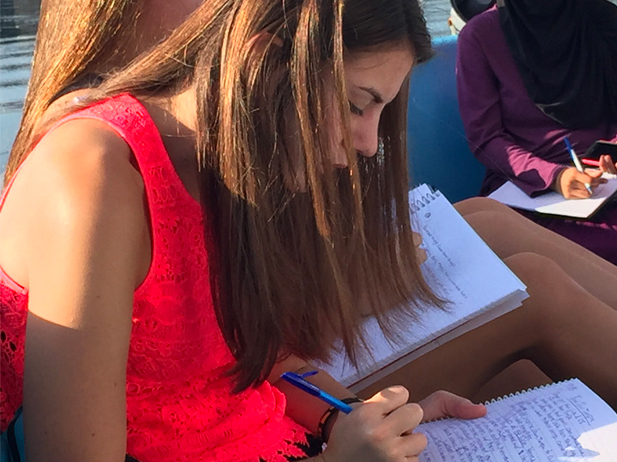 Student writing on a boat