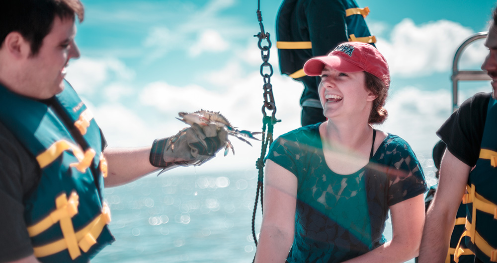 Students on a boat looking at a crab.