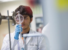 Student looking at a tube with a magnifying glass