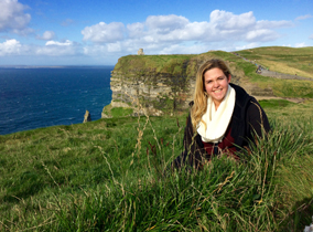 Student standing on a cliff by the ocean