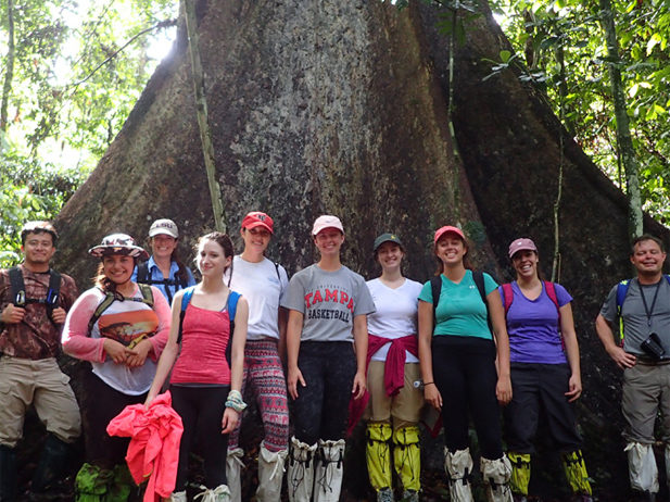 Students standing in front of the trunk of a tree