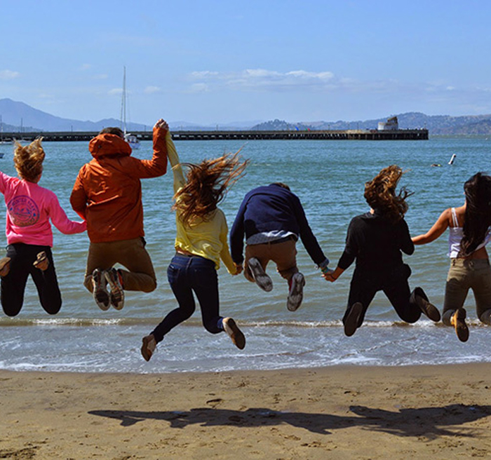 Students jumping at a beach
