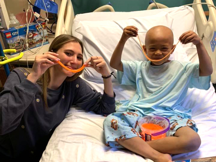 Jordan Belous '21 with a young patient in a hospital bed.