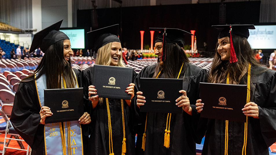 December 2021 graduates holding their diplomas