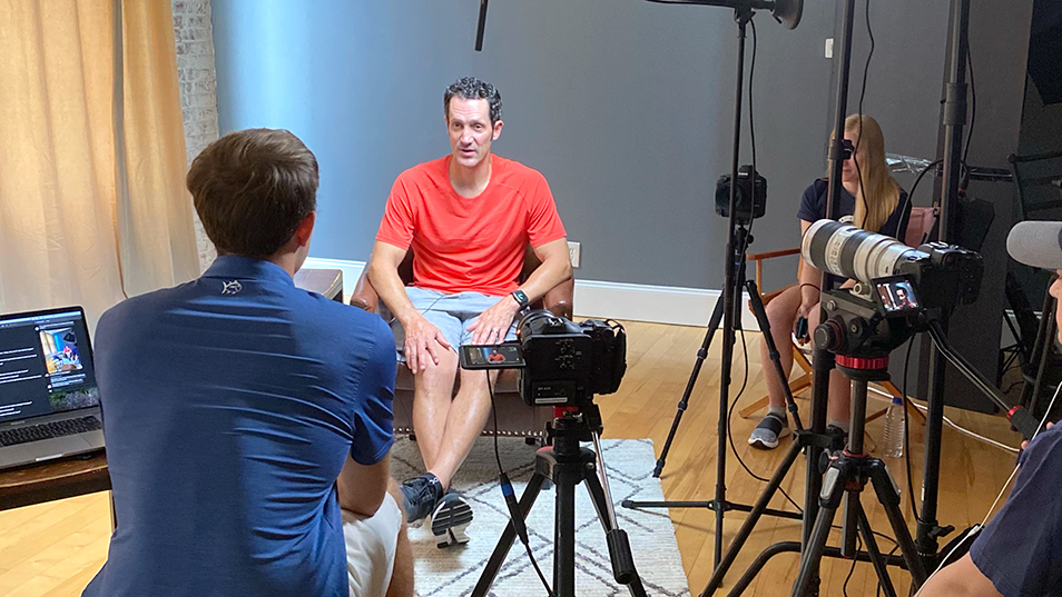 Student interviewing a gymnast on camera