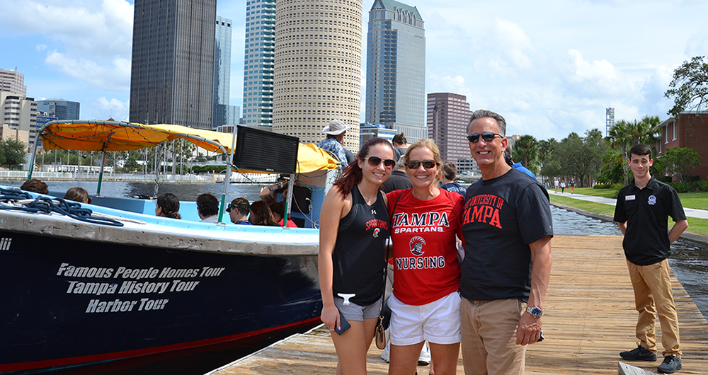 Three people posing in front of a boat